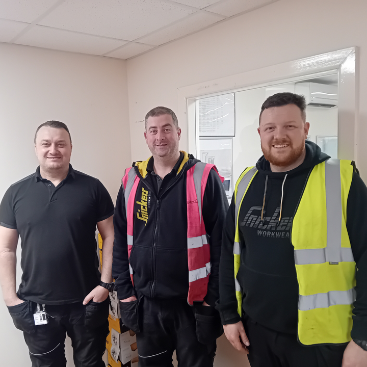 Three members of the United Drug Automation team wearing high-visibility work uniforms, posing together for a photo.